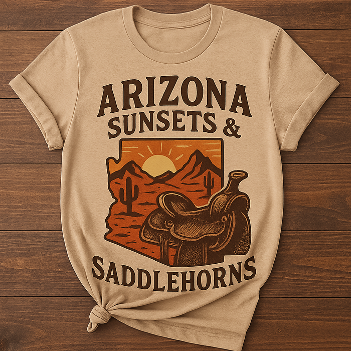 Beige t-shirt with 'Arizona Sunsets & Saddlehorns' graphic on a wooden surface