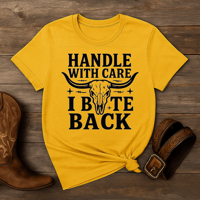 Yellow t-shirt with a skull graphic and text on a wooden surface with cowboy boots and a belt.