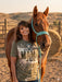 Woman standing next to a horse with a scenic background