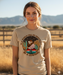 Woman wearing a t-shirt with a cowgirl graphic and text in a desert setting