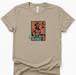 Beige t-shirt with a graphic design of a cowboy and text 'Can't be Tamed' on a white background